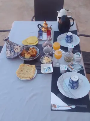 a table topped with plates of food and orange juice at Riad Kasbah Ben Hamo in Nkob