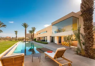 a villa with a swimming pool and a house at Palais des jardins in Ouarzazate