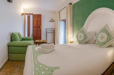 a bedroom with a white bed and a green chair at Riad Rayhana Fes-Luxury Stay Fes Medina in Fès