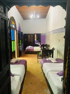 a room with three beds and a piano in it at Riad Zahraa Al Ismailia in Meknès