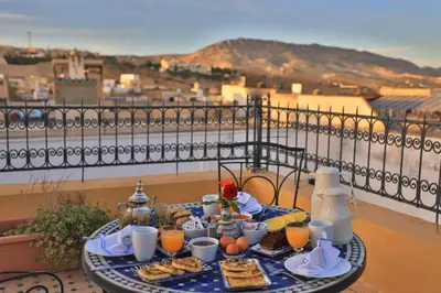 a table with breakfast food and orange juice on a balcony at Riad Louna Fes & Spa in Fès