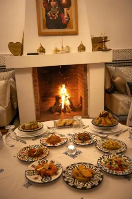 a table with plates of food in front of a fireplace at Riad Louna Fes & Spa in Fès