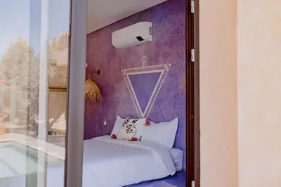 a bedroom with purple walls and a bed with a window at Villa de luxe in Marrakech