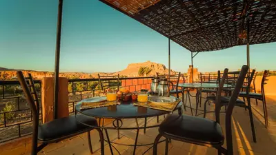 two tables and chairs on a balcony with a view of the desert at Riad Zaytoune in Ouarzazate