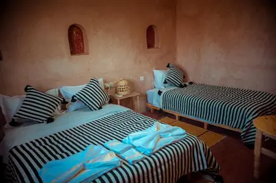 a room with two beds and a table at Riad Zaytoune in Ouarzazate