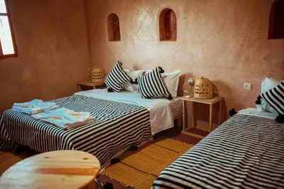 a bedroom with two beds with striped pillows at Riad Zaytoune in Ouarzazate