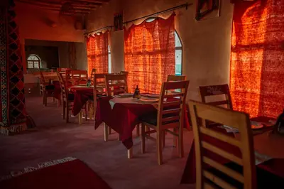 a dining room with tables and chairs with red curtains at Riad Zaytoune in Ouarzazate