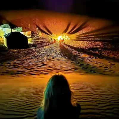 a person sitting in the water at night at Merzouga Dunes Luxury Glamping Camp in Merzouga