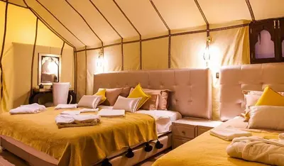 a room with two beds in a tent at Merzouga Dunes Luxury Glamping Camp in Merzouga
