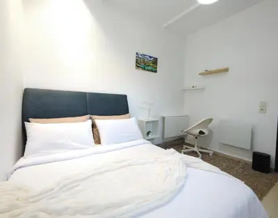 a bedroom with a large white bed and a chair at Jolie appartement à Ifrane calme et spacieux in Ifrane