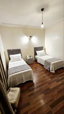 two beds in a room with a couch and wooden floors at Maison Chafik in Fès