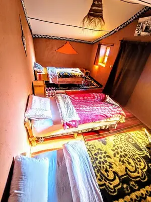 two twin beds in a room with a rug at The dune camp in Mhamid
