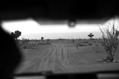 a black and white photo of a dirt road at The dune camp in Mhamid