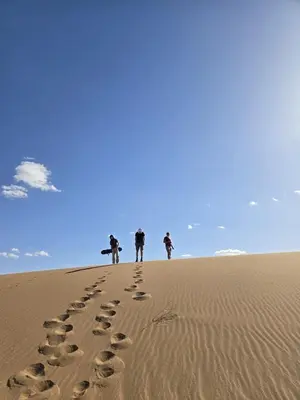 a group of people walking in the sand at The dune camp in Mhamid