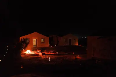 a house with a fire in the yard at night at The dune camp in Mhamid