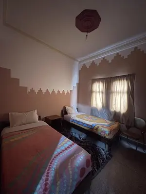 a bedroom with two beds and a window at Taghadoute Hotel in Tazenakht