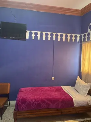 a bedroom with a bed with a purple wall at Taghadoute Hotel in Tazenakht