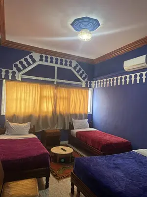 a bedroom with two beds and a blue wall at Taghadoute Hotel in Tazenakht
