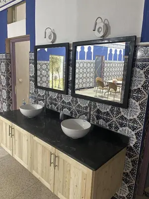 a bathroom with two sinks and two mirrors on a counter at Taghadoute Hotel in Tazenakht