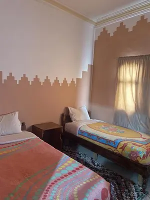 a bedroom with two beds and a window at Taghadoute Hotel in Tazenakht