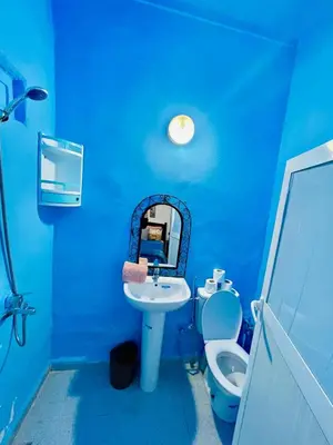 a blue bathroom with a sink and a toilet at Blue Star Hostel in Fès