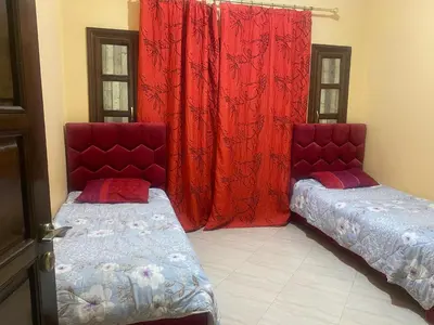 two beds in a room with red curtains at Meknes in Meknès