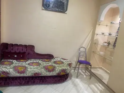 a bedroom with a bed and a chair and shelves at Meknes in Meknès