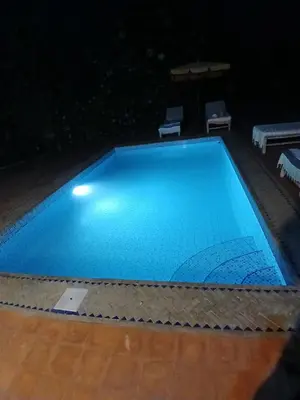 a large blue swimming pool at night at فيلا رياض عمران in Douar Blidene