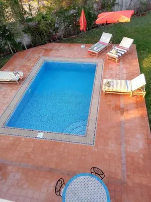 a swimming pool with two chairs and a table at فيلا رياض عمران in Douar Blidene