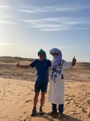 two men standing in the sand in the desert at Erg Chegaga Charming Camp in El Gouera