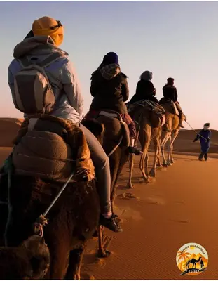 a group of people riding camels in the desert at Morocco wonderland in Merzouga