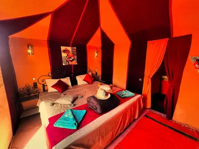a bedroom with a large bed with orange walls at Morocco wonderland in Merzouga