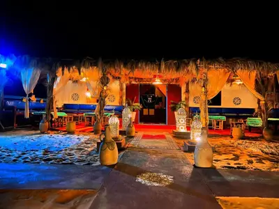 a resort entrance with a resort with chairs and umbrellas at Morocco wonderland in Merzouga