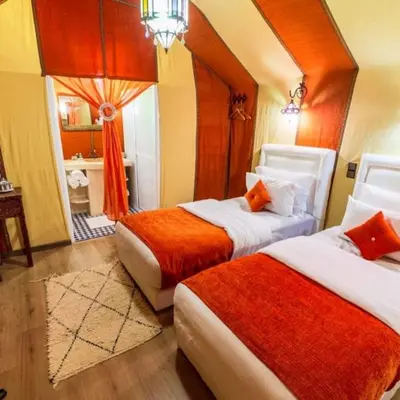 a hotel room with two beds and a bathroom at Cleopatra luxury camp in Merzouga