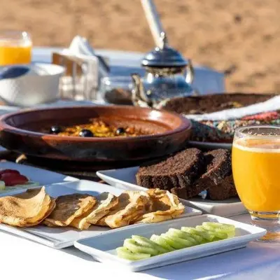a table with food and a bowl of food and orange juice at Cleopatra luxury camp in Merzouga