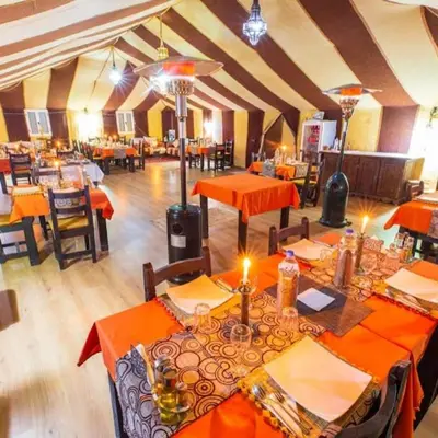 a dining room with orange tables and chairs at Cleopatra luxury camp in Merzouga