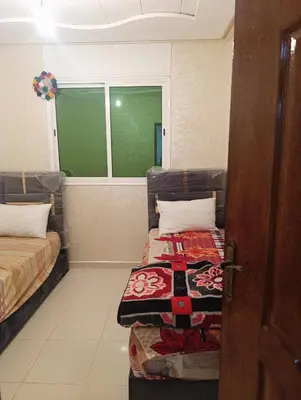 a room with two beds sitting next to a window at Appartement tradimoderne in Mrhila