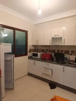 a kitchen with white cabinets and a red appliance at Appartement tradimoderne in Mrhila