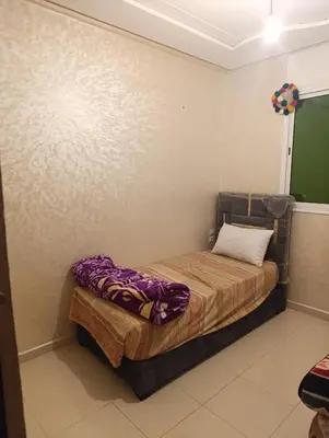 a small bedroom with a bed with purple sheets at Appartement tradimoderne in Mrhila