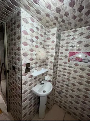 a bathroom with a white sink and a tiled wall at بدون اسم in Fès