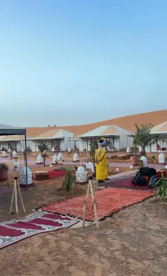 a person in a yellow raincoat standing on a rug at eclipse du desert in Merzouga