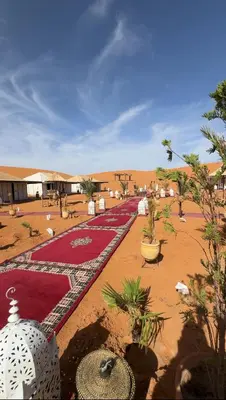 a compound in the middle of a desert with plants at eclipse du desert in Merzouga