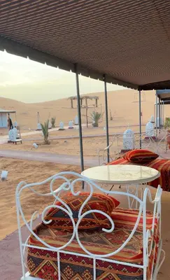 a table and chairs in the middle of the desert at eclipse du desert in Merzouga