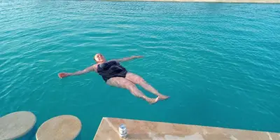 a man jumping into the water in the ocean at Kasbah Du Berger & Piscine in Merzouga