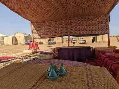 a table with bottles on it in front of a tent at Camp azmamar in Mhamid