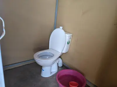 a bathroom with a toilet and a pink bucket at Camp azmamar in Mhamid