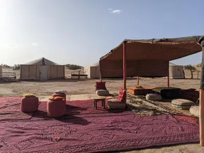 a group of chairs sitting on a rug in the desert at Camp azmamar in Mhamid