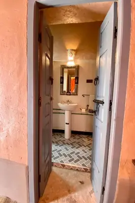 a hallway leading to a bathroom with a sink at Nomadic Birdway in Imiter