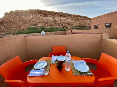 an orange table and chairs with plates and water bottles at Nomadic Birdway in Imiter