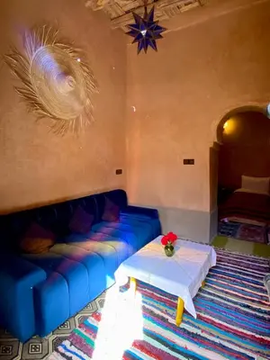 a living room with a blue couch and a table at Nomadic Birdway in Imiter